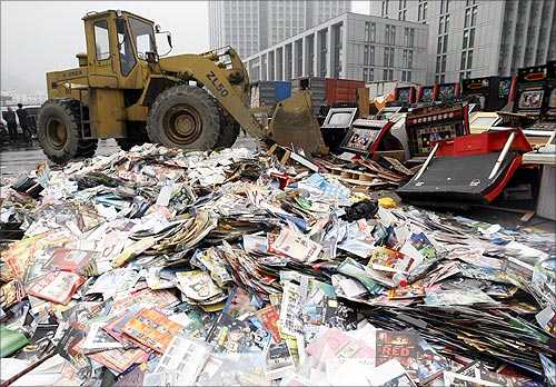 An excavator destroys confiscated pirated publications and illegal video game machines during a campaign against piracy in Hangzhou.