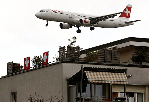 An Airbus A321-111 of Swiss International Air Lines is seen behind an apartment building during its approach for a landing at Zurich Airport.