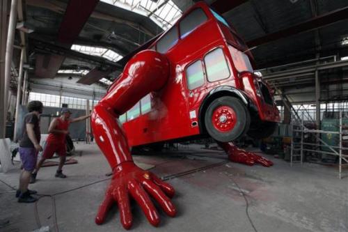 Workers check the function of the hydraulic arms of a London bus that is being transformed into a robotic sculpture.