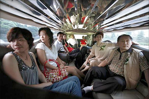 Family members of a couple getting married sit inside a Hammer Limousine on the drive to the wedding reception in Shanghai.