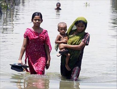 Women move through a flooded road.