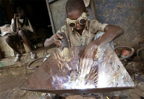 An Ivorian child welds in a wrought iron workshop in Abidjan, Ivory Coast.