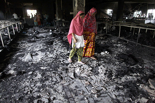 Workers visit a burnt garment factory after a fire which killed more than a hundred people in Savar.