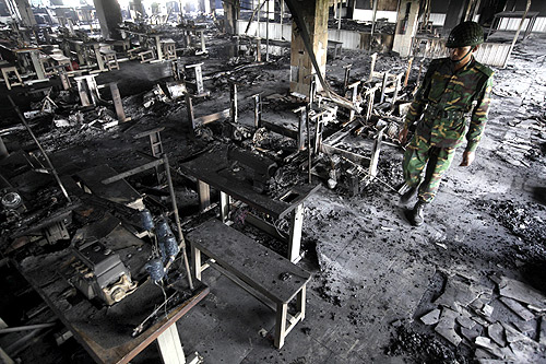 An army personnel inspects the burnt machineries of a garment factory after a devastating fire in Savar.