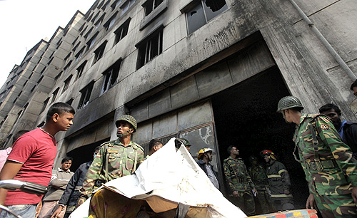 Army personnel load the body of a dead garment worker onto a rickshaw van after a devastating fire in a garment factory in Savar.