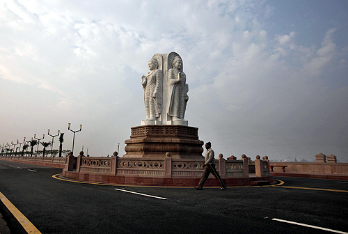 man walks in front of Buddha statues outside the Ambedkar memorial park in Lucknow.