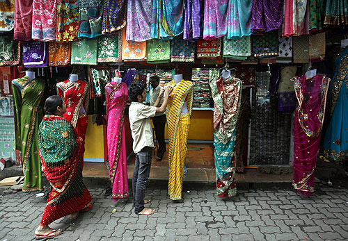 worker arranges sarees, a traditional cloth used for women's clothing outside a shop in Mumbai.