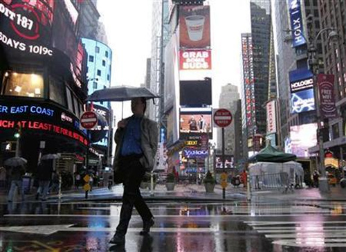 A man walks through Times Square as a massive rain storm drenched New York.