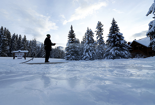 A hotel employee at Baker Creek Lodge  in Banff National Park sprays water down as he makes a ice skating rink near Lake Louise,  Alberta.