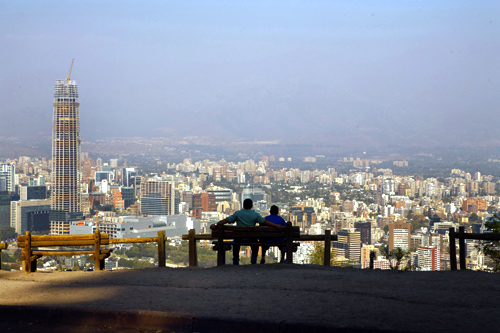 A man (L) sits with his son while enjoying the view of the Andes Mountains Range at the San Cristobal Hill in Santiago de Chile.