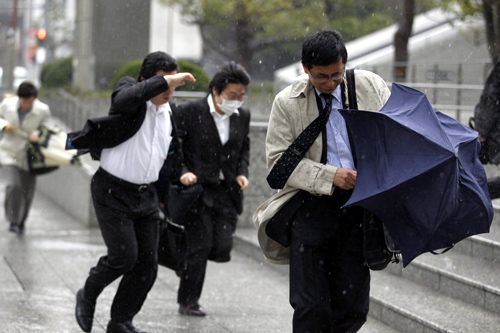 People brave the strong wind and rain in Tokyo April 3, 2012. Strong winds which hit Japan.