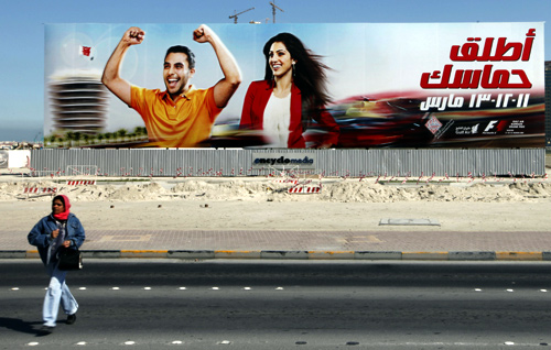 A woman walks in front of an advertisement for the Bahrain Formula One Grand Prix in Manama.