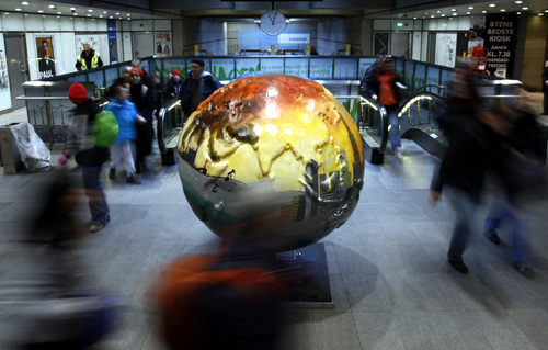 People walk past a globe as they leave a metro station in Copenhagen.