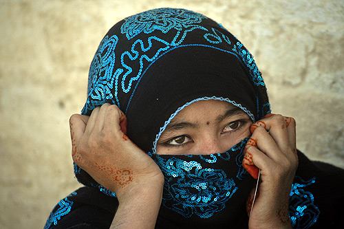 An Afghan woman with her hands decorated with henna sits while waiting to go back to Afghanistan from a United Nations (U.N.)-funded repatriation centre.
