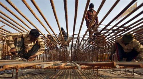 Labourers work on iron rods at the construction site of a flyover at Noida in Uttar Pradesh.