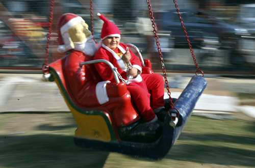 A boy dressed in a Santa Claus costume rides on a merry-go-round outside a church during Christmas celebrations in Jammu.