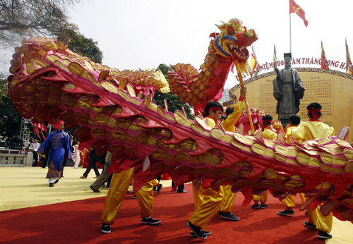 People perform the dragon dance in front of King Ly Thai To's statue.