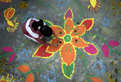 Students put the finishing touches to a rangoli, or a mural made out of coloured powders, at a school ahead of Diwali festival celebrations in Jammu.