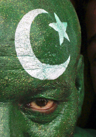 A man with his face painted depicting the colours of the Pakistan national flag.