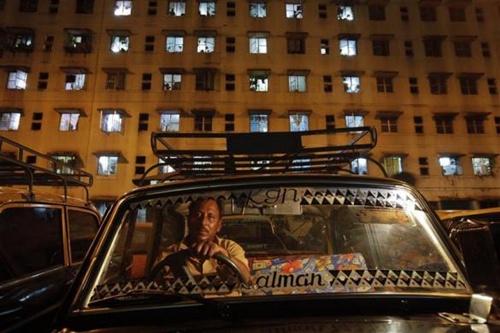 A driver waits for customers in front of an apartment building in his Premier Padmini taxi in Mumbai's suburbs.