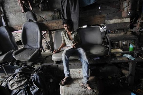 A mechanic sits on a seat salvaged from a scrapped Premier Padmini taxi at a workshop in Mumbai.