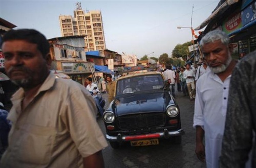 A Premier Padmini taxi makes it way through pedestrians and vehicle traffic on a crowded street in Mumbai. 