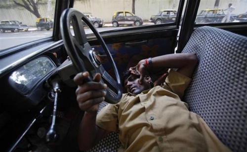 A taxi driver takes an afternoon nap with his hand on the steering wheel of his Premier Padmini taxi in Mumbai.
