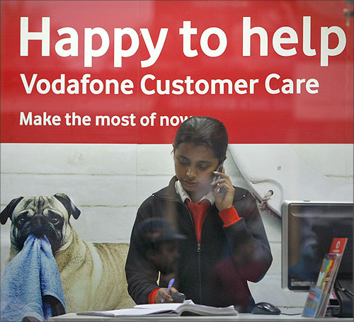 An employee talks on mobile phone inside a Vodafone store in Agartala.