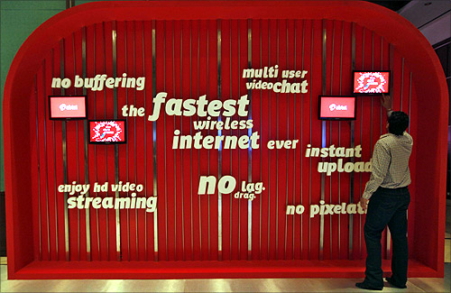 A man touches a screen on a Bharti Airtel advertisement billboard during the launch ceremony for 4G services in Kolkata.