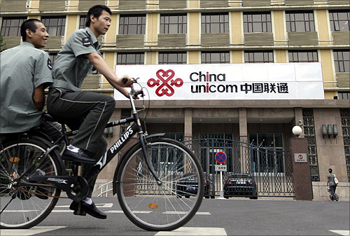 Security guards ride past a China Unicom office in Beijing.