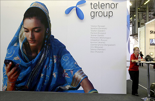 A visitor rests under a Telenor Group sign at the GSMA Mobile World Conference in Barcelona.