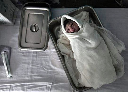 A newborn baby wrapped in bandages lies in a tray just after delivery inside the labour room at a government hospital in Kasbathana village in Baran district in Rajasthan.