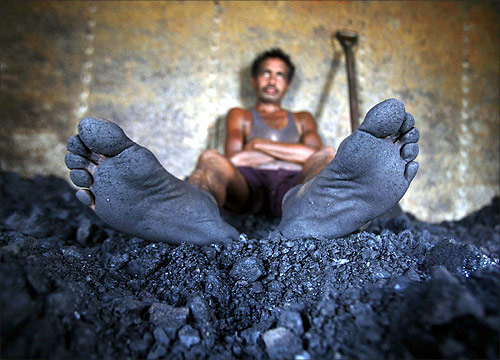 A labourer rests inside the wagon of a coal train as he takes a break from shovelling coal at a coal yard on the outskirts of Jammu.