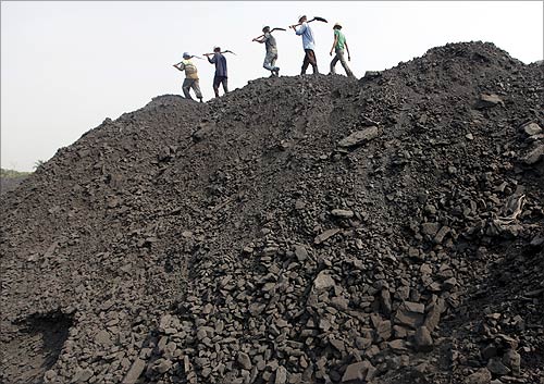 Workers walk on a heap of coal at a stockyard of an underground coal mine in the Mahanadi coal fields at Dera, near Talcher town in Orissa.