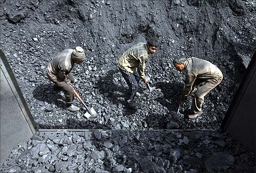 A worker shovels coal at a wholesale coal shop on the outskirts of Agartala.