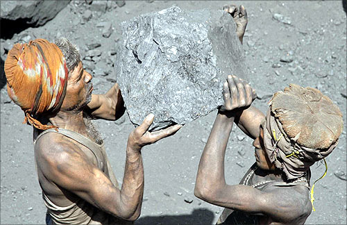 Labourers carry coal to load onto a truck at a coal yard on the outskirts of Allahabad.