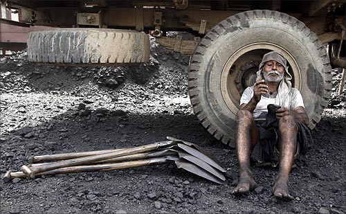 A labourer smokes after loading coal onto trucks at a coal yard near Chiwaki railway station in Allahabad.