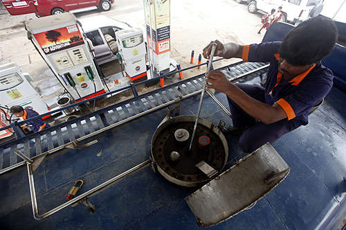 An employee measures diesel in a tanker before unloading at a fuel station in Kolkata.