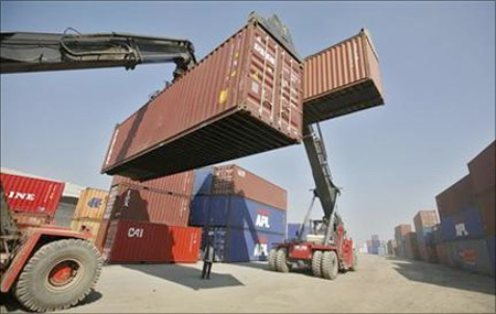 Workers prepare to stack containers at Thar Dry Port in Sanand in Gujarat.