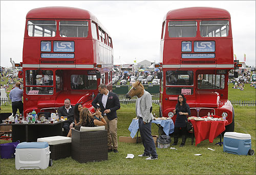 Spectators picnic between a pair of double decker buses during Ladies Day at the Epsom Derby festival in Epsom, southwest of London.