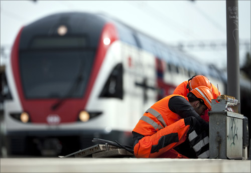 Employees of the Swiss Federal Railways (SBB) perform maintenance operations in front of the new regional two-floor train connecting Geneva and Lausanne.