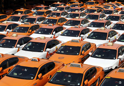 An engineer (top R) checks taxis parked at the compound of a taxi company, after drivers halted their operations to attend a nationwide strike in Seoul.