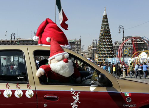 A Santa Claus plush toy is seen on the window of a taxi it drives past Zocalo Square in Mexico City.