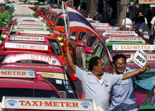 Taxi drivers wave a Thai flag during a rally in front of the Government House in Bangkok.