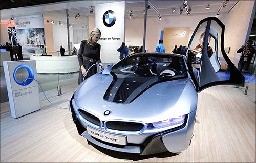 A model poses next to a BMW electric i8 Concept car during a press preview day at the AMI Auto Show in Leipzig.