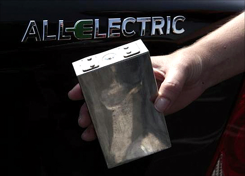 A woman displays a 333 volt single-cell battery in front of a Coda sedan at the sixth annual Alternative Transportation Expo and Conference (AltCar) in Santa Monica, California.
