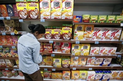 An employee arranges breakfast cereals on the shelves of a supermarket in Mumbai.