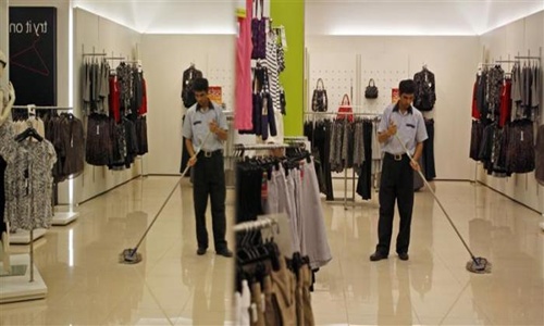 A worker is reflected in a mirror as he sweeps the floor at one of the retail outlets of Marks and Spencer in Mumbai.