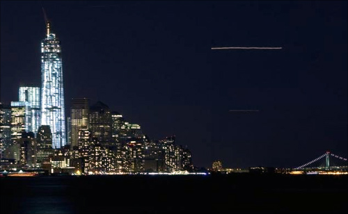 The lights of an airplane landing at La Guardia airport streak across the sky past the new World Trade Center (left) in New York.