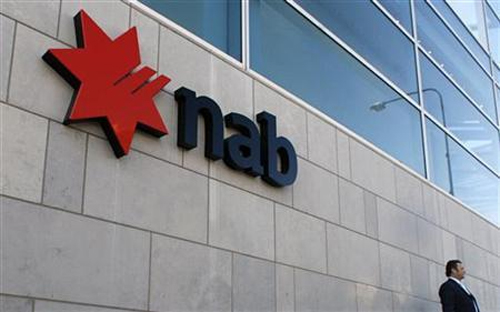 An office worker waits next to a branch of National Australia Bank (NAB) in east Sydney.